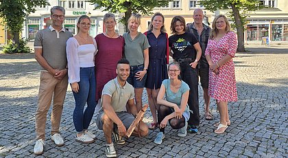 Auf dem Foto sind eine Gruppe von Menschen zu sehen. Sie stehen in zwei Reihen und lächeln. 
