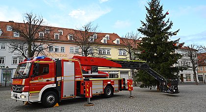 Auf dem Foto ist ein Weihnachtsbaum und ein Feuerwehrauto zu sehen. 