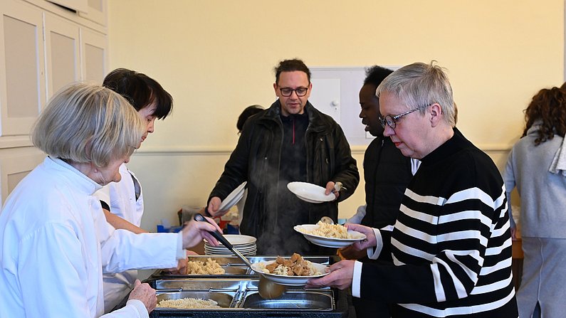 Auf dem Foto sieht man Menschen bei einer Essensausgabe. 