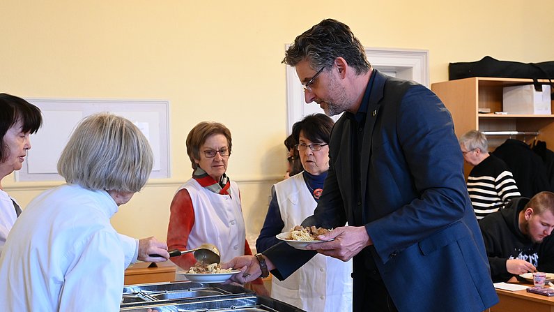 Auf dem Foto sieht man Menschen bei einer Essensausgabe. 