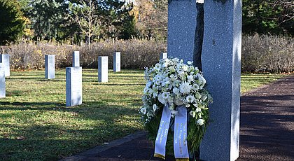 Auf dem Foto ist die Kriegsopferstele auf dem Arnstädter Friedhof zu sehen. Davor steht ein Gedenkkranz von Stadt und Landkreis. 