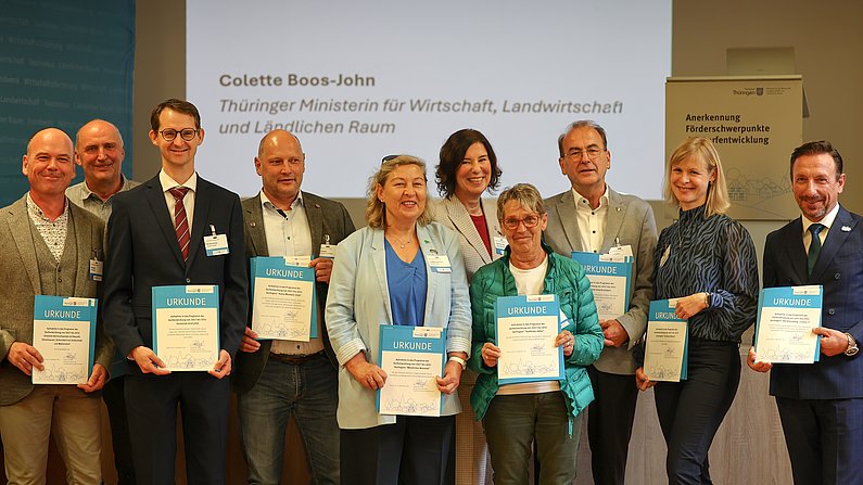Auf dem Foto sind 10 Personen zu sehen. Sie stehe in zwei Reihen - Männer und Frauen. Alle lächeln freundlich in die Kamera. 