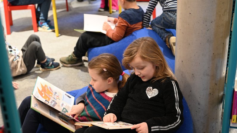Auf dem Bild sind zwei lesende Kinder zu sehen. 
