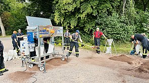 Auf dem Bild ist ein Sandsackfüllmaschine im Einsatz zu sehen. 